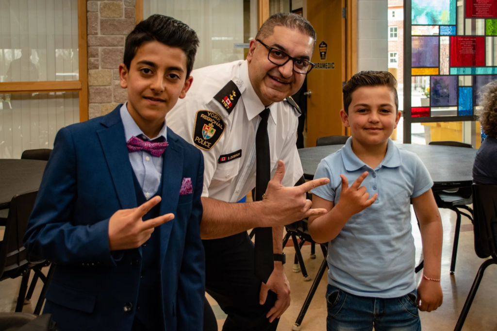 Police officer standing with two boys, all are smiling