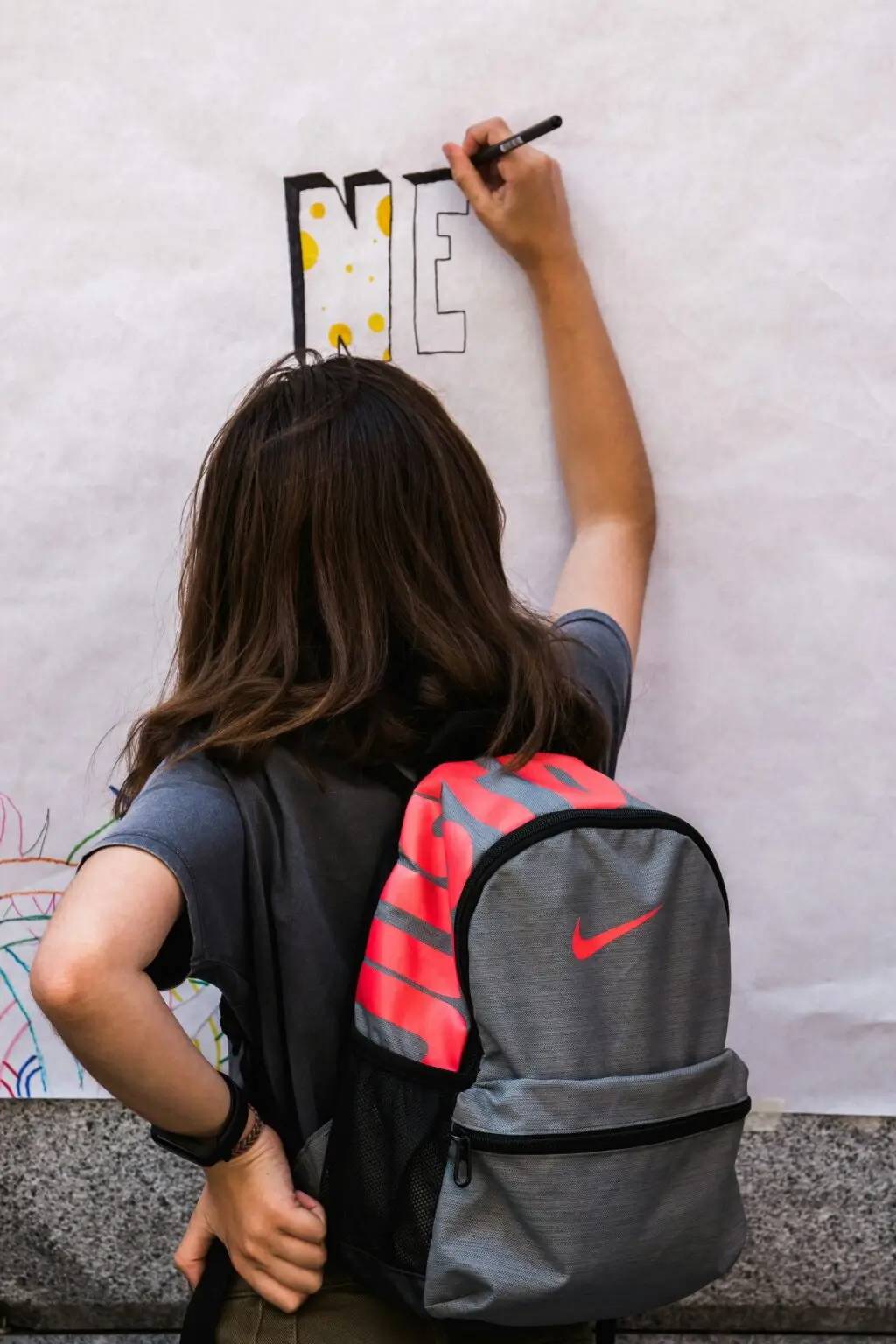 Girl wearing a knapsack writing on a white board