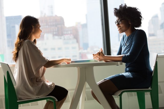 Two women sitting across a table talking